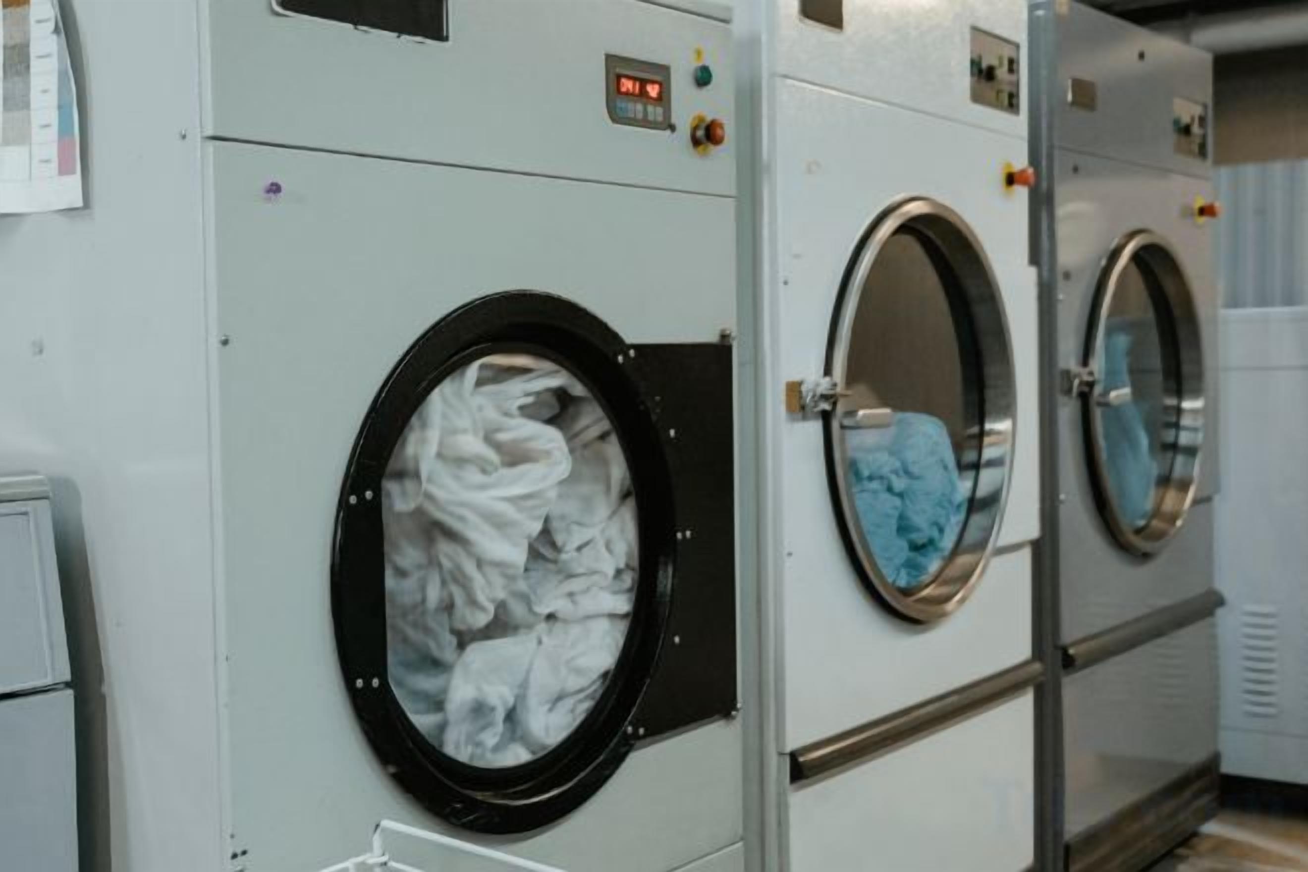 A row of industrial-style laundry machines with control panels and a digital display.