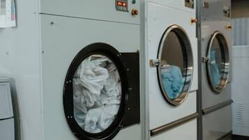 A row of industrial-style laundry machines with control panels and a digital display.