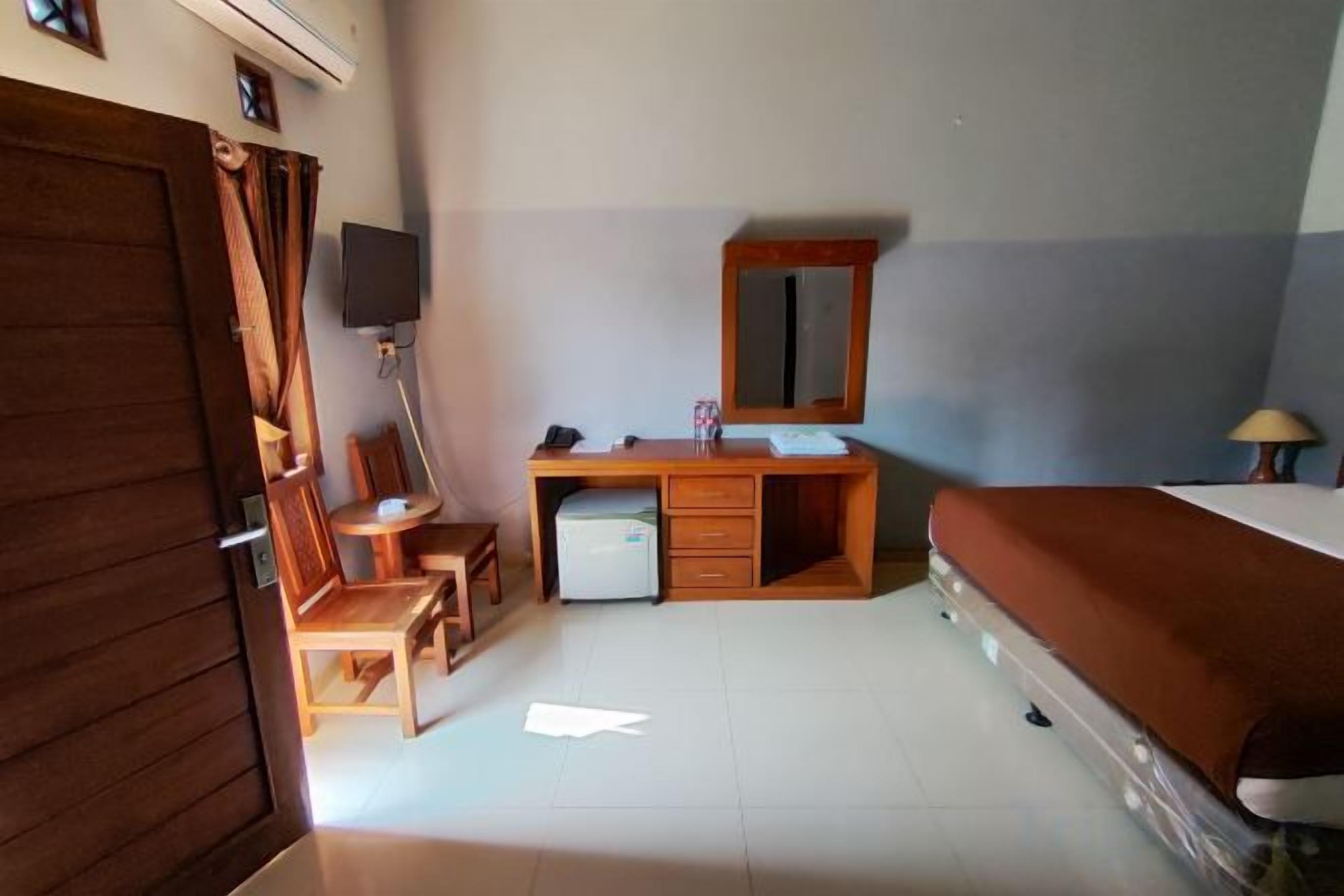 A room with a bed, a desk with a chair, a television, and a small refrigerator.