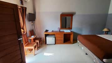A room with a bed, a desk with a chair, a television, and a small refrigerator.
