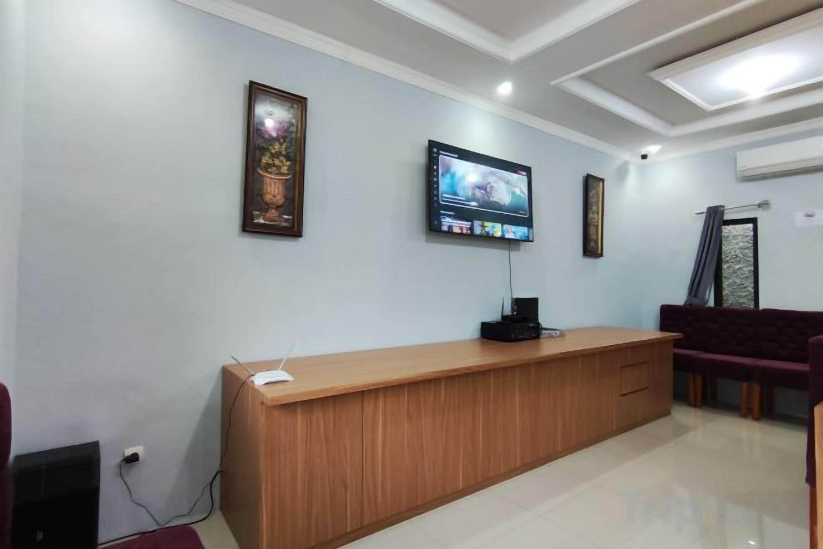 A reception area with a wooden reception desk, a flat-screen TV mounted on the wall, and a purple sofa.