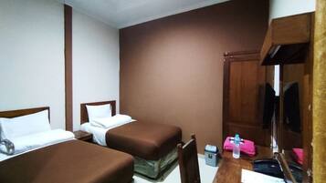 Une chambre d’hôtel avec deux lits simples, un bureau en bois avec une chaise, une petite table et un miroir.