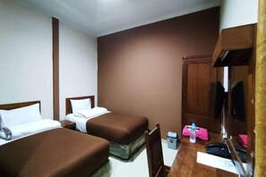 Een hotelkamer met twee eenpersoonsbedden, een houten bureau met stoel, een klein tafeltje en een spiegel.