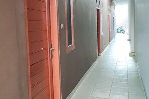 A corridor with doors, a tiled floor, and a motorcycle in the distance. - HOTEL CIWANGI (Bungursari)