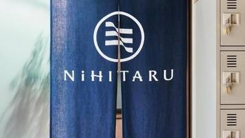 A blue curtain with a logo and the name 'NiHiTarU' hanging in a room with a wooden floor and a cabinet with keys.