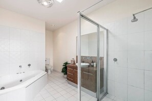 Ein modernes Badezimmer mit einer gläsernen Duschkabine, einer Badewanne und einem WC.