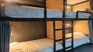 Une chambre avec un lit superposé, un mur en bois et des rideaux.