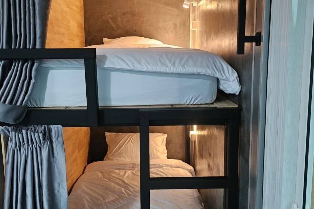 En våningssäng med vita sängkläder och en trägav.