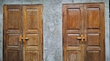 Two wooden doors with a simple latch mechanism, set against a plain wall.