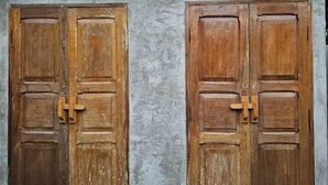 Deux portes en bois, avec un mur à texture derrière.