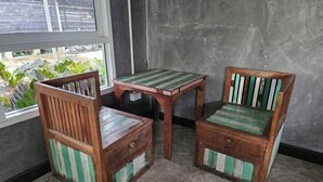 Une pièce avec une fenêtre, deux chaises en bois et une petite table.