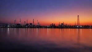 Une vue sur les toits d’une ville au crépuscule, avec des bâtiments industriels et une tour imposante.
