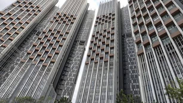 Un edificio alto con varios pisos, líneas verticales y balcones.