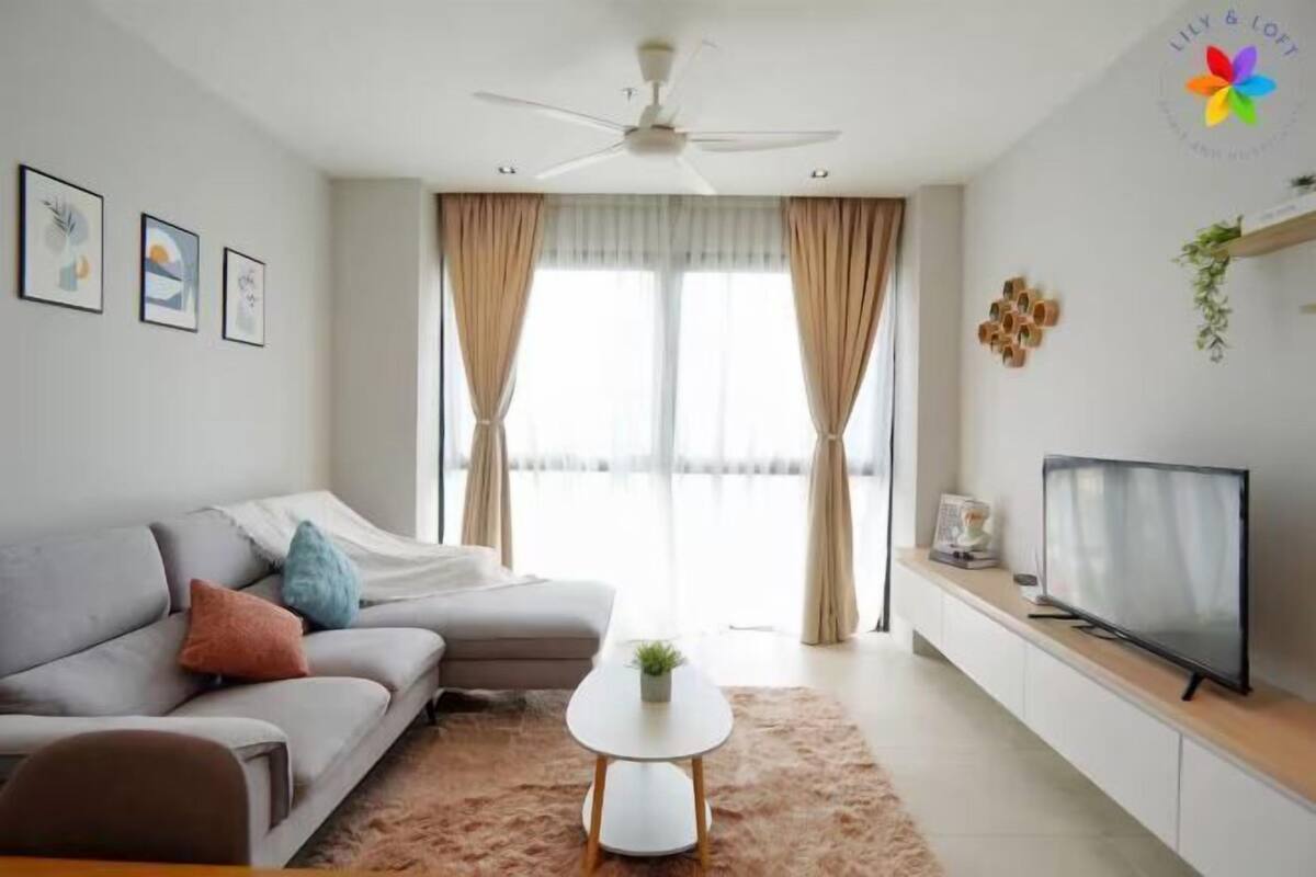 A modern living room with a sofa, a coffee table, a TV, and a ceiling fan.