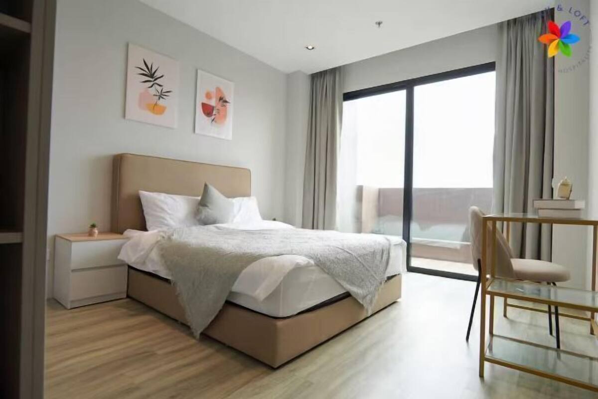 A modern hotel room with a bed, bedside table, and a view of the outside.