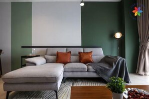 Una sala moderna con un sofá seccional gris, una mesa de centro de madera y una planta pequeña.