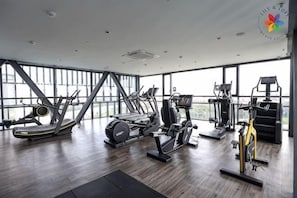 A gym with cardio machines, weight training equipment, and a large windowed wall. - Lumi @ Tropicana PJ GolfClub Balcony 5 pax (Petaling Jaya)