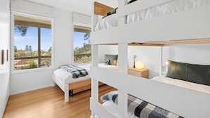 A bunk bed room with a window, a bedside table with a lamp, and a view of the outdoors. - Prasino in Central Lorne (Lorne)