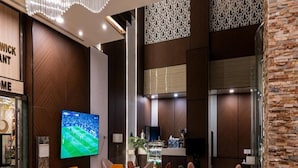 A modern lobby with a large TV, comfortable seating, and a bar area. - Dancenter Al Dabab Near King Fahad Medical City (Riyadh)