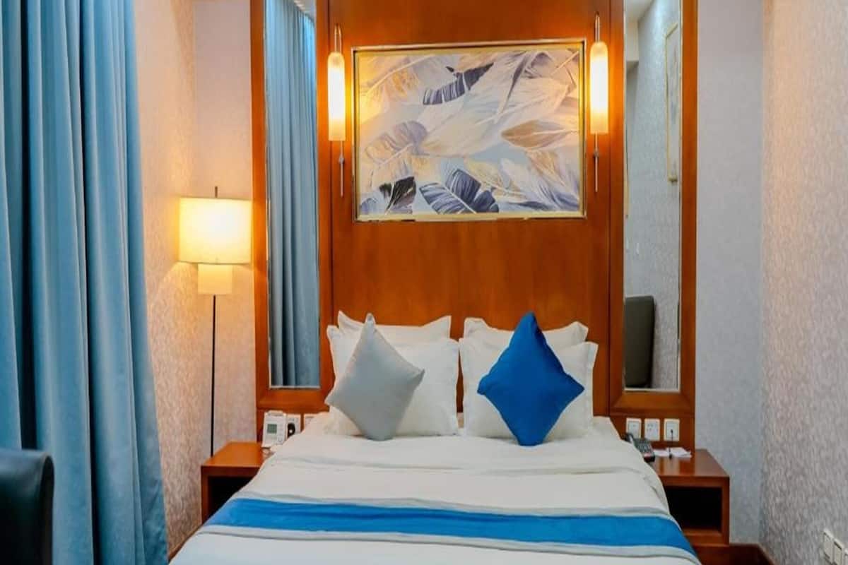 Une chambre d’hôtel avec un grand lit, une table de chevet, une lampe et un tableau au mur.