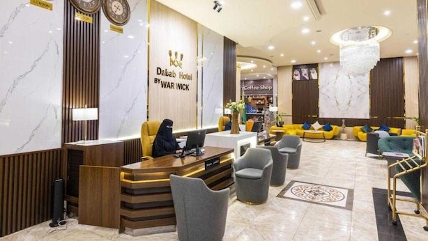 A hotel lobby with a reception desk, seating area, and a coffee shop. - Dancenter Al Dabab Near King Fahad Medical City (Riyadh)