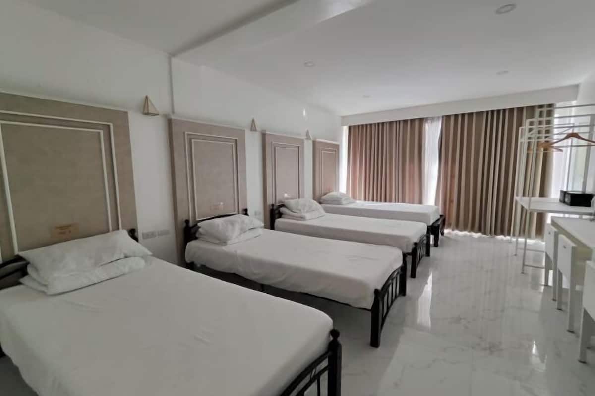 A hotel room with four single beds, a desk, and a chair.