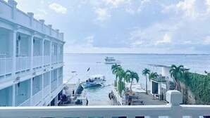 A coastal hotel with a balcony overlooking the sea, palm trees, and boats. - The Mark Resort Cebu (Lapu-Lapu City)