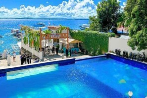 A swimming pool with a view of the sea, a bar area, and a covered seating area. - The Mark Resort Cebu (Lapu-Lapu City)