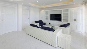 A modern living room with a white sofa set, a flat-screen TV, and built-in shelving. - The Mark Resort Cebu (Lapu-Lapu City)