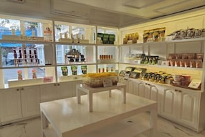 A store with shelves stocked with various packaged goods, a table in the center, and a view of the outside through the windows. - The Mark Resort Cebu (Lapu-Lapu City)