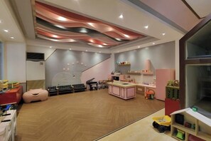 Une salle de jeux pour enfants équipée d’une scène, d’un espace pour s’asseoir, ainsi que de divers jouets et équipements de jeu.