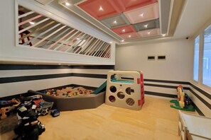 Ein Kinderzimmer mit Spielbereich, Spielzeug und einem Fenster.