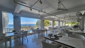 A spacious dining area with white furniture, large windows, and ceiling fans. - The Mark Resort Cebu (Lapu-Lapu City)