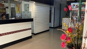 A hotel reception area with a tiled floor, a reception desk, and a potted plant with flowers. - Pattaya Inn hotel (Pattaya)