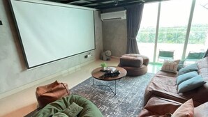 A living room with a large screen, a sofa, a bean bag, and a coffee table.