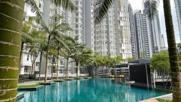 A swimming pool with lounge chairs, surrounded by tall residential buildings and palm trees.