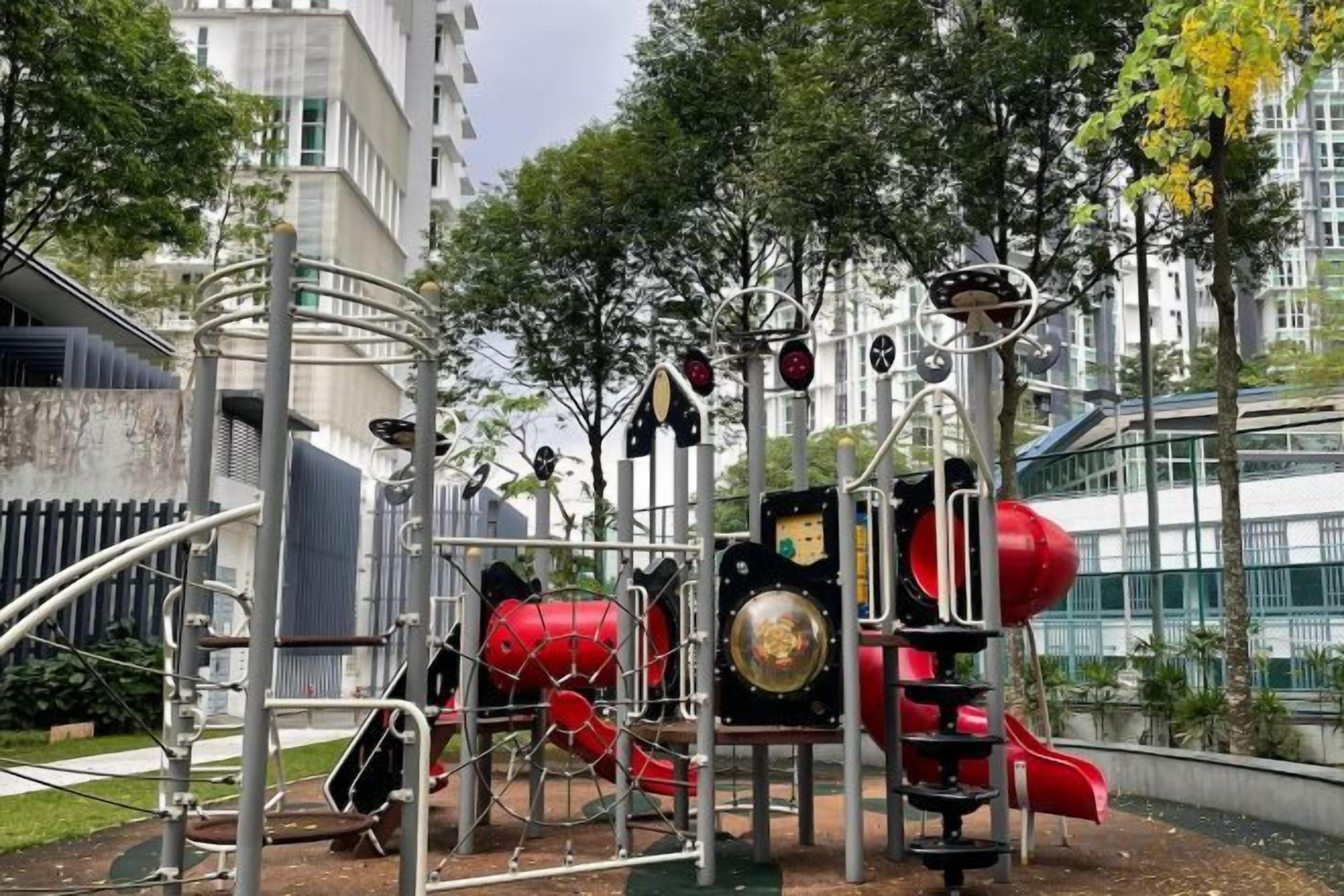 Un espace de jeux extérieur doté de diverses installations, entouré d’arbres et de bâtiments.