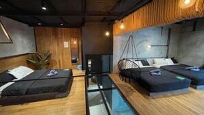 A room with two beds, a glass partition, a hanging chair, and a plant.