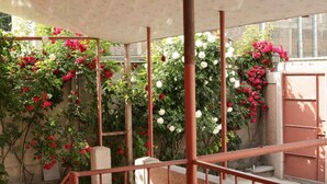 A covered outdoor area with a metal staircase and walls adorned with climbing roses. - Styopa Hotel (Yerevan)