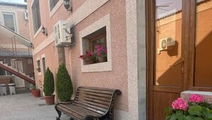 A building with a wooden bench, potted plants, and a door. - Styopa Hotel (Yerevan)