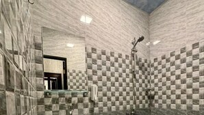 A bathroom with a checkered tile wall, a pedestal sink, and a shower. - Styopa Hotel (Yerevan)