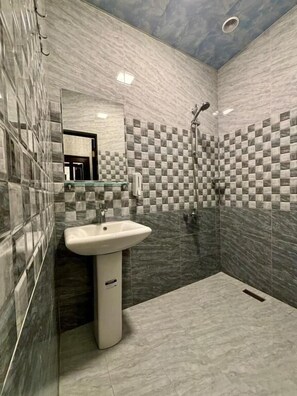 Habitación triple familiar, vista al patio | Baño | Amenidades de baño gratuitas, secadora de cabello, pantuflas, toallas