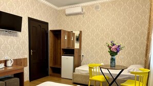 A hotel room with a bed, a desk with a chair, a small table with a vase of flowers, a television, and a wardrobe. - Styopa Hotel (Yerevan)