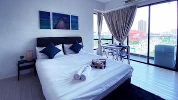 A hotel room with a large bed, a desk, and a view of the city.