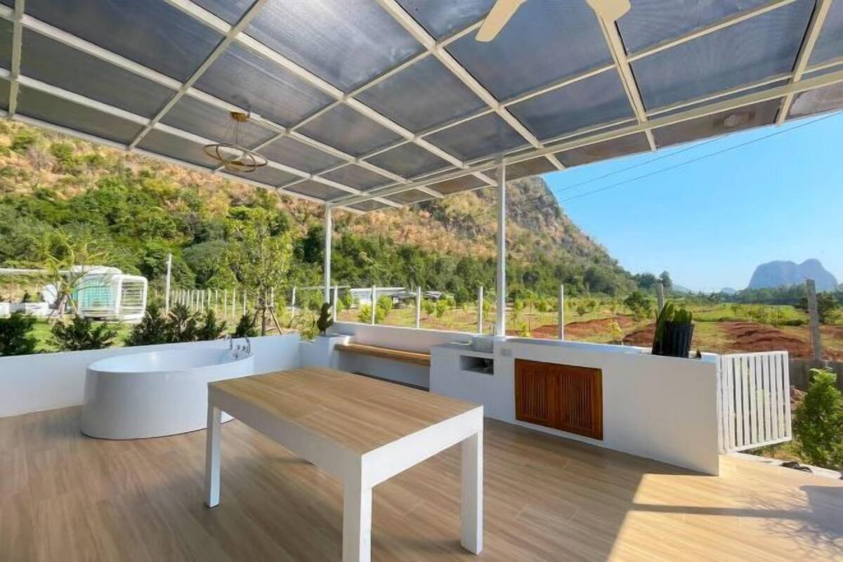 A modern outdoor space with a wooden table, a white bench, and a bathtub.