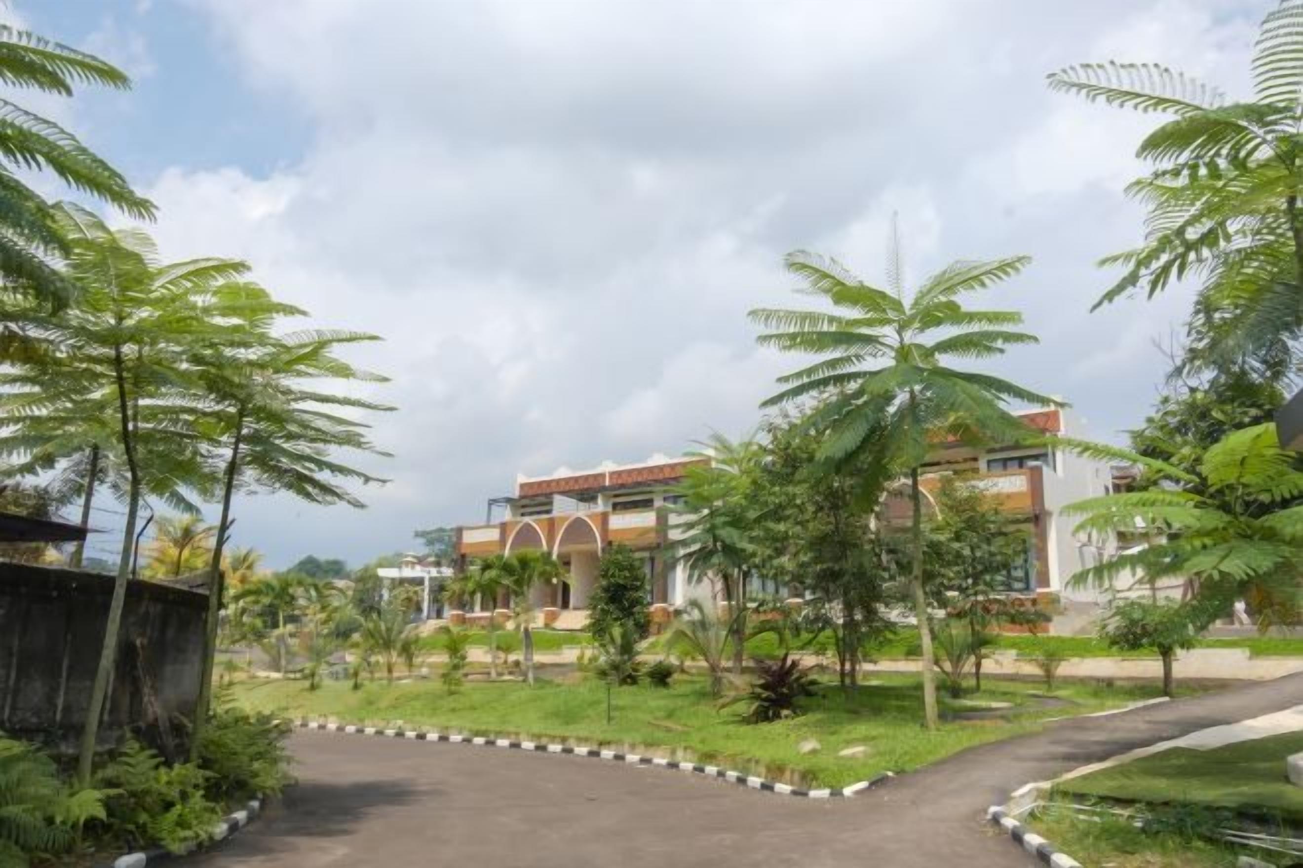 A landscaped area with a curved pathway leading to a building with multiple floors and a modern architectural style.
