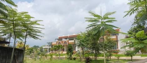 A landscaped area with a curved pathway leading to a building with multiple floors and a modern architectural style.