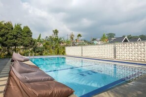 A swimming pool with a white wall and a row of lounge chairs. - Salma Syariah by TwoSpaces, Bogor (Cisarua)