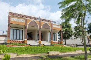 A two-story house with a balcony, a covered porch, and a well-maintained garden. - Salma Syariah by TwoSpaces, Bogor (Cisarua)
