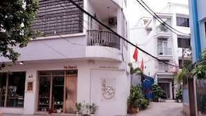 A building with a storefront labeled "The August" and a sign indicating "Coffee and Pastries." There are potted plants in front of the entrance. - WE stayin Saigon Ben Thanh Market City View Studio (Ho Chi Minh City)